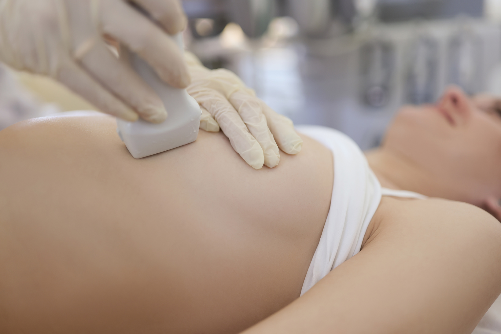 Doctor Doing Ultrasound Scan of Breast to Young Woman in Clinic Closeup